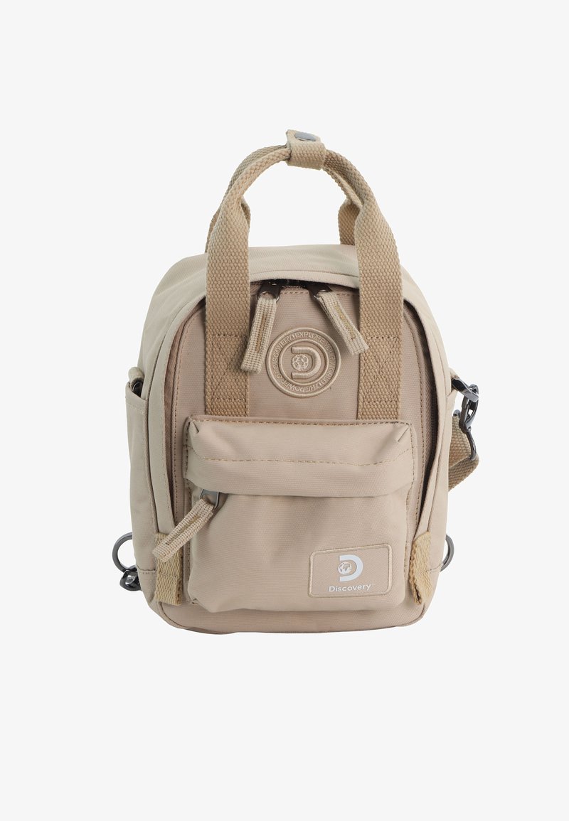 Beige canvas backpack with two top handles, front pocket, and side loops. Zipper closure with logo patch and textured fabric details.