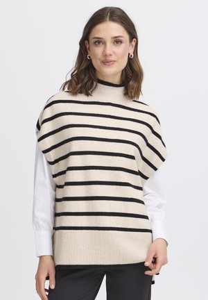 Beige und schwarz gestreifter gestrickter Pullover mit hohem Kragen, oversized Passform und geripptem Saum, über einem weißen Langarmshirt getragen.