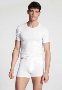 T-shirt blanc en coton à manches courtes et boxer, texture lisse, design ajusté, style minimaliste, sans motifs ni logos visibles.