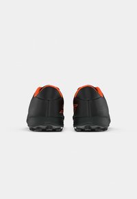 Black athletic shoes with orange accents, featuring a low-cut design and textured rubber outsole for traction. Logo visible on the side.