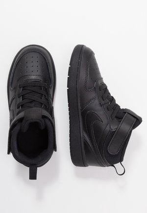 Paar zwarte hoge sneakers met veters en klittenbandsluitingen, één schoen rechtop en de andere van bovenaf gezien, op een witte achtergrond.