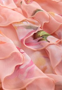 Tela rosa suave y transparente con bordes fruncidos y patrones florales en verde, blanco y varios tonos de rosa y naranja.