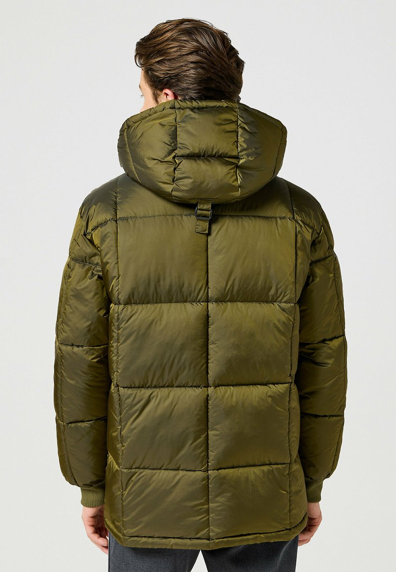 Olíva zöld puffajkó magas gallérral, steppelt kivitelben, bordázott mandzsettákkal és egy kis hurokkal a hátsó részén az állíthatóság érdekében.