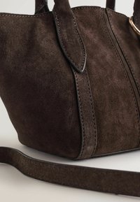 Barna szarvasbőr kézitáska sima textúrával, lapos fogantyúkkal és hosszú, levehető pánttal. Varrt díszítésekkel és finom csillogással rendelkezik.