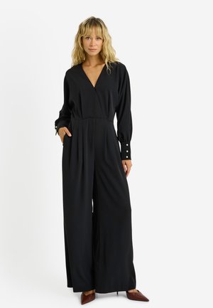 Mono negro con mangas largas, escote en V, bolsillos laterales y detalles de botones en los puños. Tela fluida con un diseño de pierna ancha y relajado.