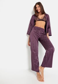 Paarse satijnen slaapset bestaande uit een kimono-stijl bovenstuk met brede mouwen, gecombineerd met gestreepte broek in de bijpassende kleur.