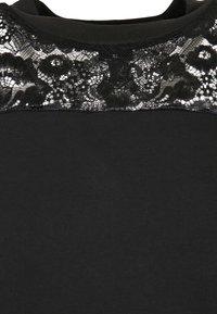 Haut noir à manches courtes avec un empiècement en dentelle aux motifs floraux. Le corps est en tissu lisse, légèrement texturé.