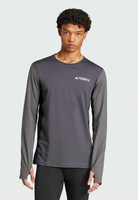 Hallide toonidega pika varrukaga sportlik särk, mis on valmistatud kerge kaaluga, niiskust imava materjaliga ning mille rinnal on peen TERREXi logo.