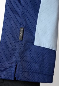 Nike treningsskjorte i marineblå mesh-stoff med perforeringer, lyseblå detaljer, og en sidespalte med et merke som indikerer "Avansert Pusteegenskaper."