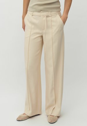 Pantalons larges de couleur crème fabriqués dans un tissu doux et léger. Comprend des plis à l'avant, des poches latérales et une taille avec cordon de serrage.