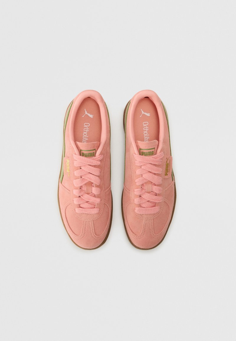 Baskets en daim rose clair avec une forme arrondie, présentant une surface texturée, un design à lacets et une semelle extérieure en caoutchouc marron.