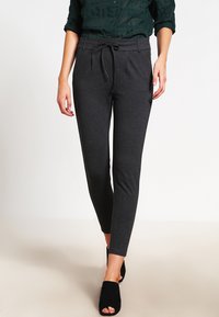 Sive tailored jogger hlače napravljene od mekanog materijala, s elastičnim pojasom, uskim krojem i glatkom teksturom.