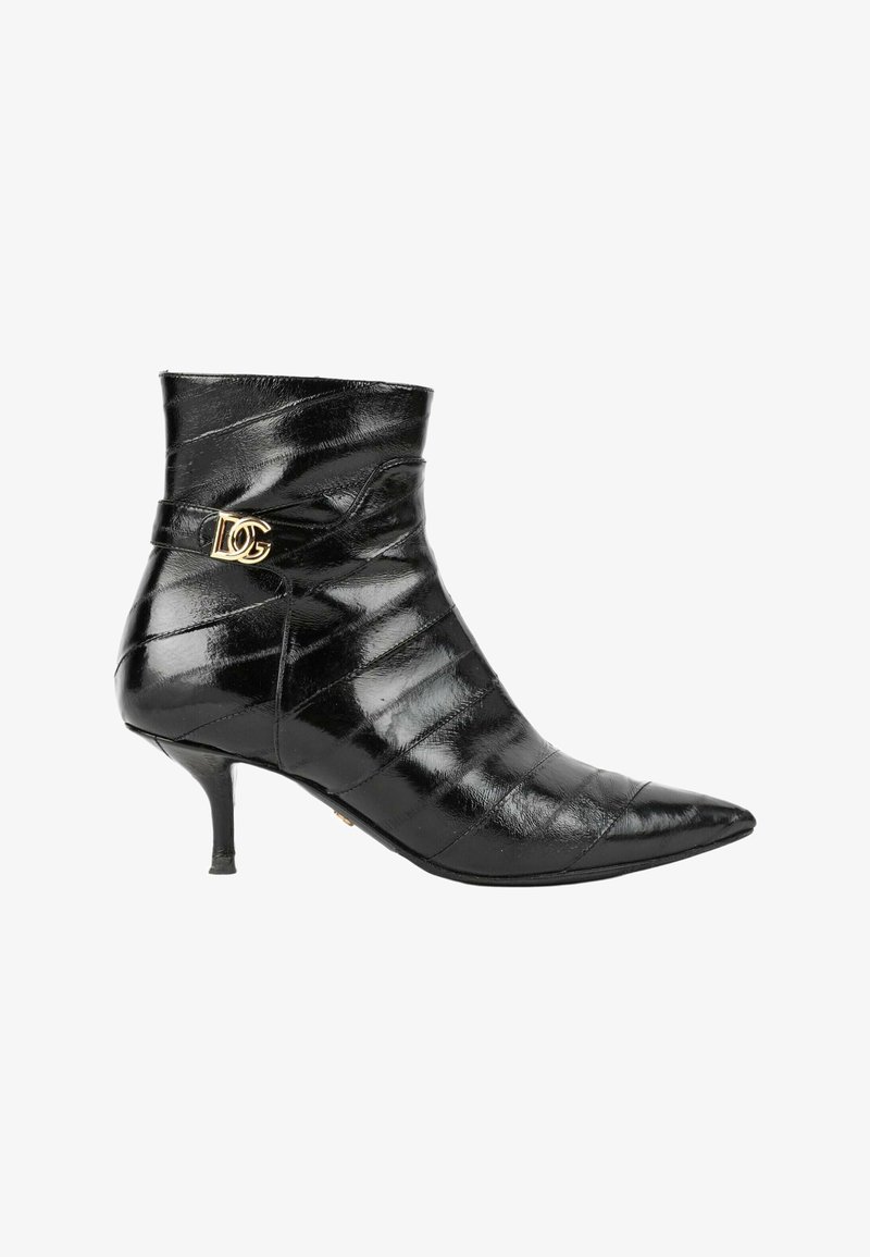 Bottine noire brillante à bout pointu avec un petit talon kitten fin et une boucle décorative dorée sur la bride latérale.