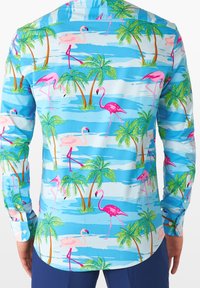 Camisa de manga larga azul con estampado de flamencos rosas y palmeras verdes sobre un fondo azul claro, confeccionada con una tela ligera.