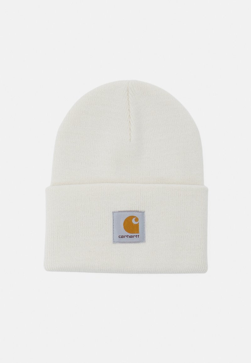 Knit beanie, cream color, features a folded cuff, and a square logo patch with yellow and gray accents. Soft texture, simple design.