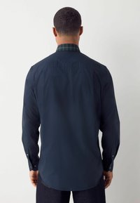 Marineblauw overhemd met lange mouwen en een geruite groene kraag, met knopenmanchetten, een gladde textuur en een rechte zoom. Ontworpen voor een getailleerde uitstraling.