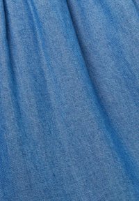 Tissu en denim de bleu moyen avec une texture lisse et un léger éclat, présentant des variations subtiles et un motif tissé tout au long.