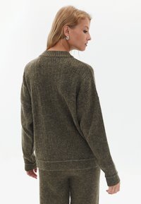 Olivgrüner Strickpullover mit gerippter Textur, lockerer Passform und langen Ärmeln. Verfügt über einen runden Ausschnitt und dezente Nahtdetails am Saum.