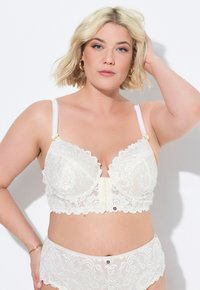 Lace bralette in ivoorkleur met geschulpte randen, onderbedekking, verstelbare banden en decoratieve knopen aan de voorkant, met bijpassende slipjes.