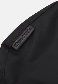 Musta synteettinen kangas, jossa on sileä tekstuuri; siinä on musta nahkapäällyste, jossa on kohokuvioitu brändinimi "Marc O'Polo" kiinnitettynä.