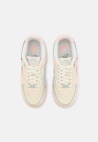 Sneakers beige in pelle con accenti rosa pastello e azzurro chiaro, punta forata e lacci bianchi. Presentano il marchio Nike e il nome del modello sulla linguetta.