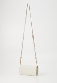 Biely crossbody vak vyrobený z textúrovaného materiálu, s dlhým nastaviteľným popruhom a zlatými reťazovými akcentmi. Kompaktný obdĺžnikový tvar.