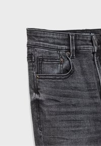 Jeans de mezclilla gris oscuro con un corte ajustado, que cuentan con un bolsillo frontal, remaches de cobre y una textura suave. Sin marcas ni patrones visibles.