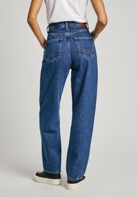 Jeans visokog struka, širokog kroja, izrađeni od plavog denima, s dva stražnja džepa, kontrastnim šavovima i kožnom oznakom brenda na pojasu.