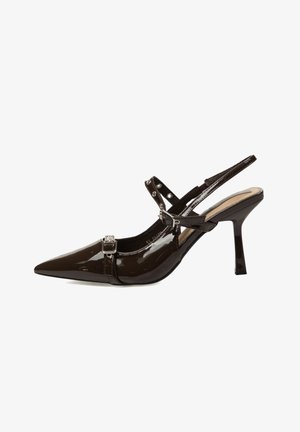 Zapato de tacón con tira trasera en charol marrón, punta puntiaguda, correa ajustable con hebilla y tacón de aguja delgado. Acabado liso y brillante.