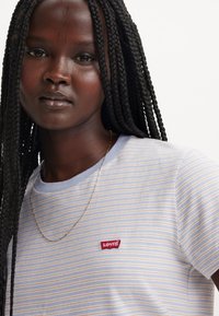 Levi's striped t-shirt in light blue and white with yellow stripes, featuring a small red logo, round neckline, and short sleeves.