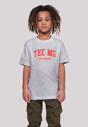 Graues T-Shirt mit kurzen Ärmeln, das mit fettem roten Text "DIE MG AUTOFIRMA" bedruckt ist. Kombiniert mit olivgrünen Cargo-Hosen.