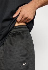 Μαύρο αθλητικό σορτς με υφή από δίχτυ, διαθέτει ελαστική μέση και μικρό χρυσό λογότυπο Nike στο πλάι.