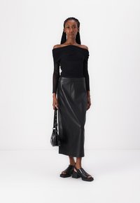 Must värviline off-the-shoulder, rüsitud pika varrukaga särk, millele on sobitatud kõrge vöökohaga must nahkpüks. Paksud mustad platvormsandaalid ja väikene must kott.