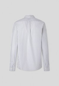 Witte lange mouwen shirt met verticale marineblauwe strepen, met knoopsluiting bij de kraag en een afgeronde zoom. Heeft knopen bij de manchetten en een centrale rugplooi.