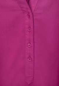 Camicia fucsia con collo a V, dotata di sei bottoni in tinta e un tessuto liscio e strutturato.