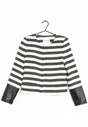 Veste à manches longues rayée noir et blanc avec poignets en cuir noir uni, présentée sur un cintre noir sur fond blanc.
