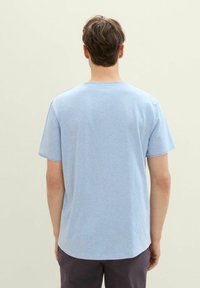 Camiseta de algodón azul claro con mangas cortas, escote redondo y un dobladillo ligeramente curvado. Textura suave, sin patrones ni acentos visibles.