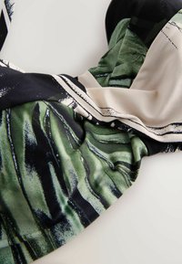 Foulard di raso con un motivo astratto di foglie verde e nero con accenti color crema, texture liscia e design fluido.