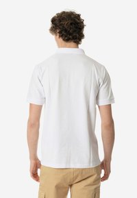 Polo shirt bianco a maniche corte con collettoclassico e taglio dritto. Presenta un tessuto testurizzato e dettagli di cucitura semplici.