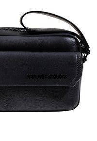 Borsa a polso in pelle nera strutturata con chiusura a pattina e logo "ARMANI EXCHANGE" impresso sul davanti.