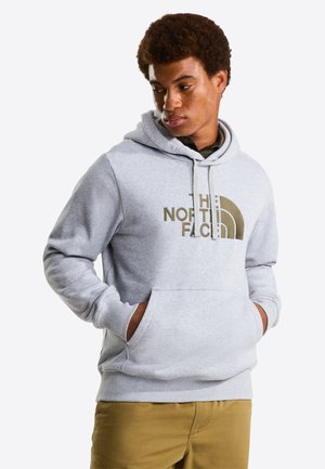 Felpa grigia con cappuccio in tessuto morbido, dotata di tasca frontale e grande logo verde oliva. Vestibilità casual con polsini e orlo a costine.