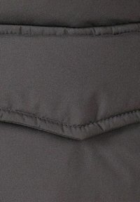 Sort polstret stof med en glat tekstur, der har en syet søm og subtil glans, hvilket indikerer et let og isoleret design.