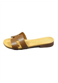 Sandalo scivoloso in pelle marrone con due ampie cinghie e una soletta sagomata. Suola piatta con una soletta beige e un sottile dettaglio di branding.