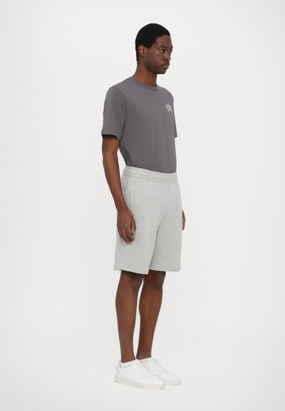 Grå bomulds T-shirt med kortærmet og lomme detaljer, parret med lysegrå bomulds shorts og hvide sneakers. Simpelt og afslappet design.