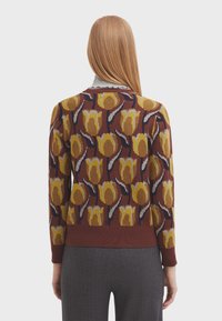 Maglione a maglia color bordeaux con un motivo floreale in giallo e grigio, con orlo a costine e colletto rotondo. Vista posteriore mostrata.