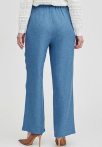 Pantaloni azzurri chiari a gamba larga con un finish testurizzato, dotati di una vita elastica. Il tessuto sembra morbido e traspirante.