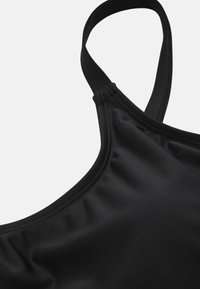 Zwarte sportbeha met verstelbare dunne banden. Glad, elastisch materiaal met een matte afwerking en versterkte naden voor duurzaamheid.