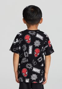 Czarna koszulka z grafiką Spider-Mana, w tym czerwone maski, wzory pajęczyny i biały logo "Marvel", wszystko na gładkiej bawełnianej tkaninie.
