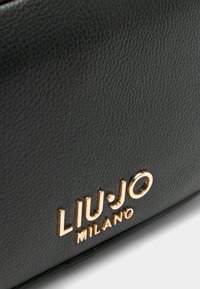 Zwarte leren handtas met een gestructureerde oppervlakt en een gouden logo "LIU JO MILANO" dat prominent zichtbaar is.
