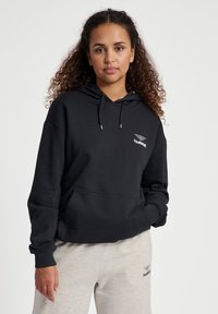 Czarna bluza z kapturem z kieszenią z przodu, sznurkiem do regulacji w kapturze oraz małym białym logo na piersi. Miękka tkanina i luźny krój.